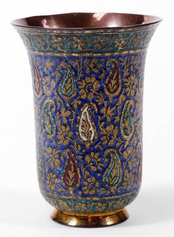 A 19thC Persian enamel and gilt metal beaker, with gilt coloured wirework floral decoration, on a blue ground with an upper green banding, the main body of bell shaped form, set with various flowers, on a circular foot, unmarked, 12cm H.