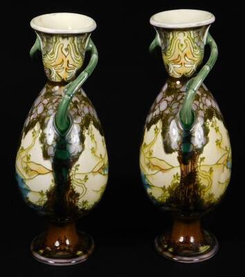 A pair of late 19thC Minton's Secessionist pottery vases, in the manner of Louis Solon, of shouldered circular form, with entwined bark handles, on oval feet, each decorated with scenery, predominately in green and purple, faint impressed marks beneath, e - 2