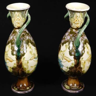 A pair of late 19thC Minton's Secessionist pottery vases, in the manner of Louis Solon, of shouldered circular form, with entwined bark handles, on oval feet, each decorated with scenery, predominately in green and purple, faint impressed marks beneath, e - 4