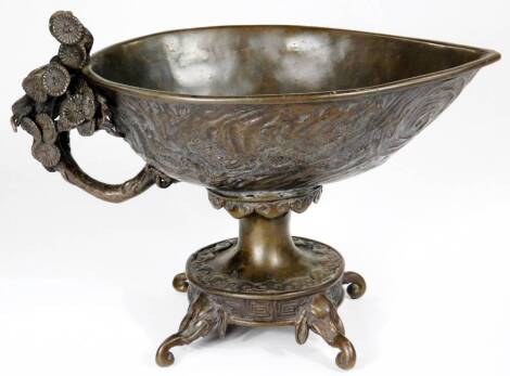 A Chinese patinated bronze vessel, with ellipse shaped bowl raised with geometric and floral patterns, with a floral handle on an inverted stem and circular foot, terminating in scroll feet, 18cm H.