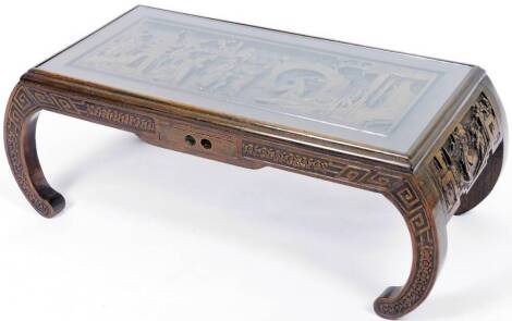 An early 20thC Chinese hardwood low table, heavily carved with figures, interior scenes, etc., on scroll legs, 35cm H, 94cm W, 45cm D. (with original receipt showing purchase in 1958)