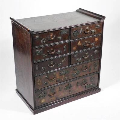 An early 20thC Japanese hardwood Shodhana table cabinet, with six short and two long drawers, each raised with various moulded figures, etc. 46cm H, 49cm W, 24cm D.