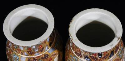 A pair of Meiji period Japanese pottery Satsuma vases, each of shouldered form, profusely decorated with panels of figures in an exterior setting, broken by a geometric pattern predominately in orange, blue and green with gilt highlights, unmarked, 21cm H - 5