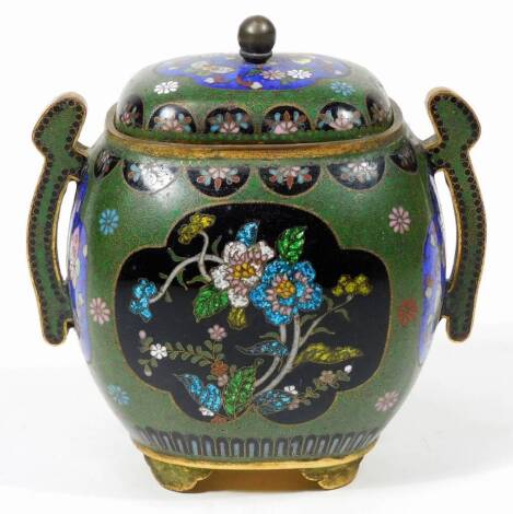 A 20thC cloisonné two handled sugar bowl, of bombe form, with shaped handles, the centre profusely decorated with flowers, on a green and black ground predominately in blue, green and yellow, on shaped feet, unmarked, 14cm H.