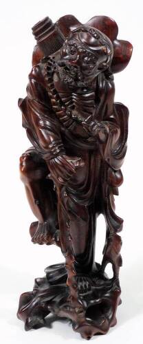 An early 20thC Chinese root carving, of a bearded sage in flowing robes holding staff in a naturalistic setting, 28cm H.