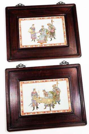 A pair of Chinese Republic porcelain wall plaques, each of rectangular form, polychrome decorated with an Imperial scene of figure in a chair flanked by further figures in flowing robes, predominately in purple, yellow and pink, with an outer geometric ba