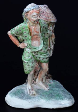 A Japanese Meiji period pottery figure, of a gentleman in flowing robes holding large basket aside tree bough, polychrome decorated predominately in green and brown, unmarked, 23cm H.