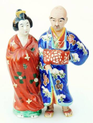 A Japanese pottery figure group, of a lady and gentleman each standing in flowing robes, predominately in brown, green and blue, on an unglazed base, 23cm H.