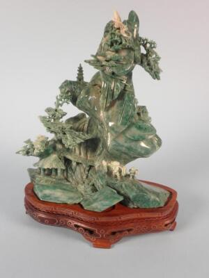 An Eastern Jadeite carving in the form a mountain with a house and trees
