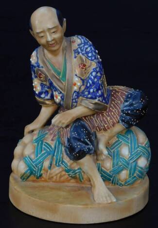 An early 20thC Japanese pottery figure, of a seated gentleman in flowing robes, polychrome decorated predominately in blue and red, on an oval foot, impressed marked JAPAN beneath, 10cm H.