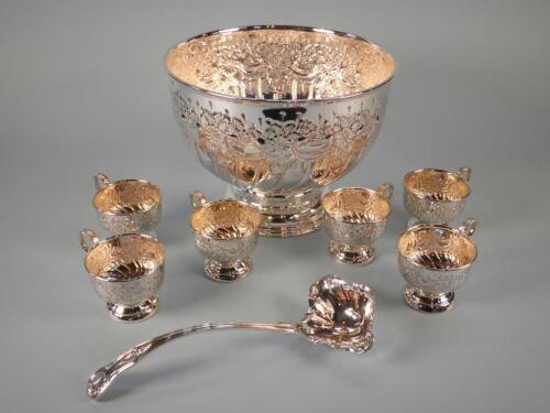 A silver plated punch bowl decorated with flowers and scrolls