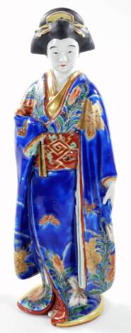 A Japanese semi porcelain figure, of a standing Geisha in flowing robes, decorated with butterflies and flowers, predominately in blue, orange and yellow with gilt highlights, 38cm H.