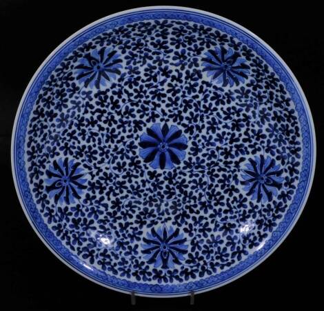 A Chinese porcelain dish, of circular form, profusely decorated with flowers in entwined stems with an outer floral border, unmarked, Ming type but later, 40cm Dia.