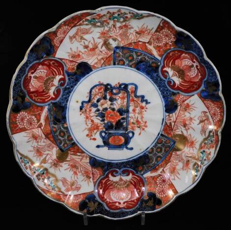 A Japanese late Meiji period porcelain Imari dish, of floral form, centred with a vase of flowers with an outer border of exotic birds and further flowers, predominately in red and blue with gilt highlights, unmarked, 31cm W.