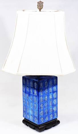 A Chinese semi porcelain table lamp, of square form set with various figures on a fixed ebonised base, with metal mounts and cream coloured shade, late 20thC, 79cm H.