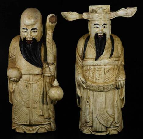 A pair of carved wooden figures of sages, one holding staff each in flowing robes, possibly with later decoration, 40cm H. (2)