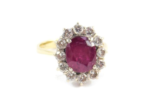 An 18ct ruby and diamond ring, the oval cut ruby, approx 3.5cts, in a surround of twelve diamonds, approx 1.08cts, size N/O, 5.4g.