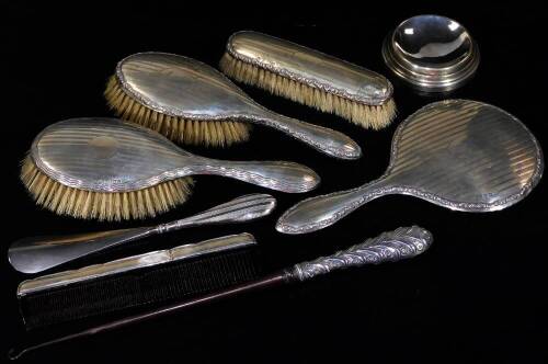 A George V silver four piece dressing table set, comprising two hair brushes, hand mirror, 25cm H, and a clothes brush, each with a vacant cartouche partially engine turned, Birmingham 1914, etc. a similar shoe horn, button hook. (a quantity)