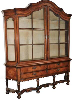 A 19thC Dutch walnut and marquetry inlaid display cabinet, the arched top profusely decorated with vases, flowers and leaves, above a pair of astragal glazed doors flanked by further arched astragal panels revealing shaped shelves, the sub section set wit