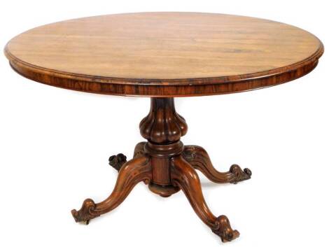 A Victorian rosewood tilt top loo table, of oval form with moulded border on a shaped gadrooned stem and quadruple scroll feet, 78cm H, 114cm W, 93cm D.