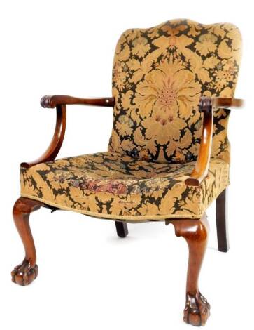 A late 19thC mahogany framed armchair, with serpentine back and seat overstuffed in floral material, with shaped scroll arms, on heavily carved front cabriole claw and ball feet, possibly Irish, 97cm H.