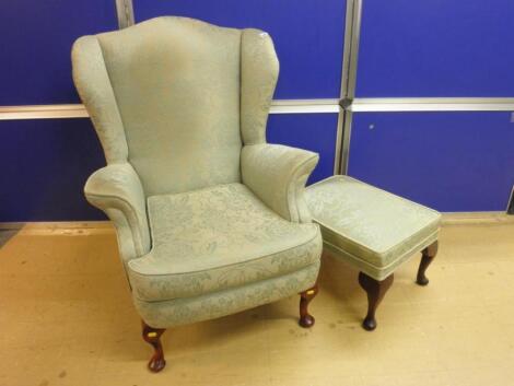 A wingback armchair upholstered in dark green and pale green damask type