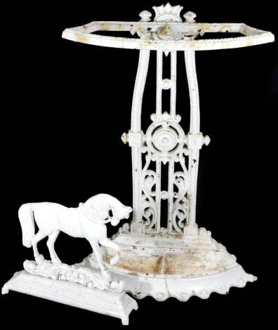 A late 19thC cast iron umbrella stand, with shaped top, pierced back set with scrolls and gadrooned sections with two umbrella compartments, on a shaped base, painted white, 66cm H, 45cm W, 19cm D and a cast iron door stop in the form of a horse with rais