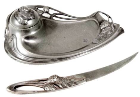 A late 19thC Art Nouveau pewter desk stand, in the manner of Liberty, of shaped form with entwined leaf decoration and opening for inkwell, with similar paper knife, no. 229, 20cm W. (2)
