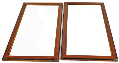 A pair of National Mt. Airy mahogany framed campaign style mirrors, each of rectangular form, with bevelled glass and ebonised outlines, broken by metal sections, 120cm H, 60cm W, 5cm D.