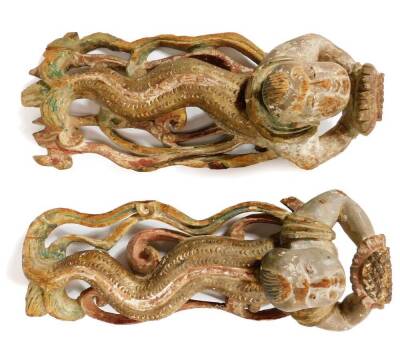 A pair of heavily carved Javanese wooden serpent child nymphs or mermen, each looking upwards on similar pierced bases, partially painted, 33cm W.