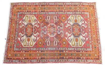 An Azerbaijan Kazak rug, with three central medallions on a red ground, enclosed by triple borders with flowers and guls, 206cm x 142cm.