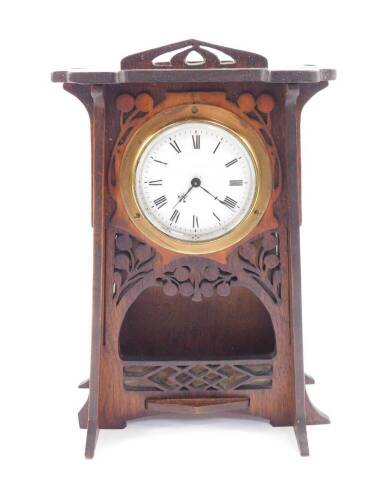 An Art Nouveau wooden cased mantel clock, circular enamel dial bearing Roman numerals, clockwork movement, the case of tapering form, with carved decoration of fruit trees, the sides with Gothic fretwork, with key, 26cm H.