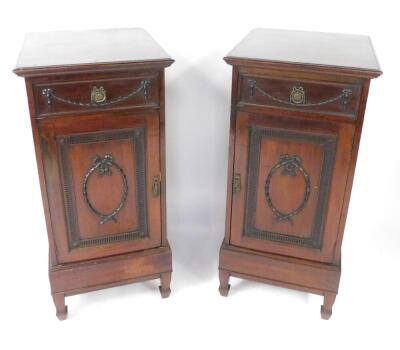 A pair of Adams style Edwardian mahogany side dining pedestals, each with a drawer carved with harebell swags, one with fitted interior, above a panelled door, having a harebell and bow tied wreath, within a fluted surround, opening to reveal a single she
