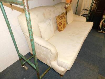 A pair of Edwardian style two seater sofas, upholstered in a floral pattern cream fabric, raised on tapering square legs, brass capped on castors, 189cm W. - 3