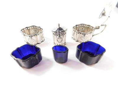 A Georgian style silver 3 piece condiment set, of serpentine form with pierced and engraved decoration, comprising mustard pot, salt and pepperette, with blue glass liners, mustard and salt spoons, cased, Birmingham 1973, 7.52 oz - 3