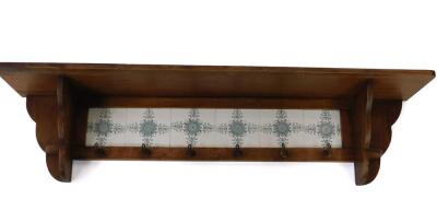 A Victorian pine wall hanging coat rack, with six floral tiled back and six hooks, 31.5cm H, 125cm W, 23.5cm D.