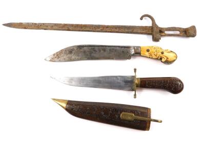 A 19thC hunting knife, possibly Indonesian with an engraved steel blade, and carved ivory and brass mounted hilt, 32cm L, together with an Indian knife, with a wooden handle carved with leaves and similarly decorated sheaf, 34cm L, and a bayonet, 51cm L.