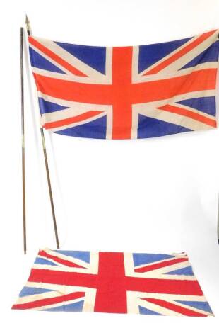 Two wooden and brass flag poles, two sections, with Union Jack flags, 225cm and 217cm H.