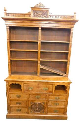 A late Victorian burr oak secretaire bookcase, the top with a breakfront cornice, carved with patera, flanked by a pair of acorn shaped urns above an arrangement of adjustable shelves with fluted support, the base with a central fitted secretaire drawer f