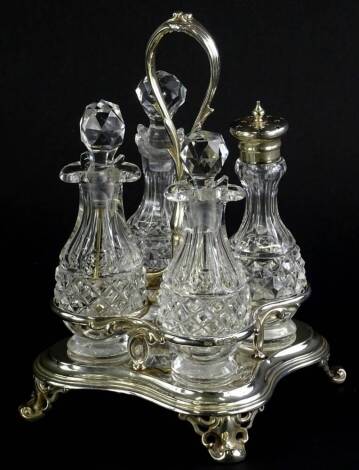 A Victorian four bottle cruet, with leaf cast scroll handle, shaped base, and four scroll cast feet, containing four cut glass bottles, three with stoppers, hallmarked for London 1858, weighable silver 9oz.