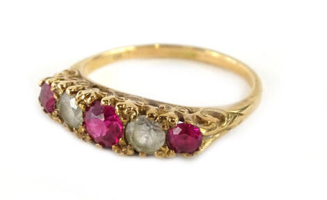 A gypsy ring, set with three rubies and two imitation diamonds, in raised scroll setting, yellow metal unmarked, ring size M, 2.8g all in.