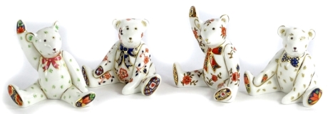 A collection of four Royal Crown Derby porcelain small bear paperweights, each wearing a bow tie and patterned feet, all boxed.