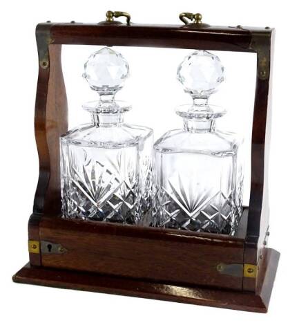 A mahogany and brass mounted two bottled tantalus, with two square section decanters and faceted stoppers, 30cm W.