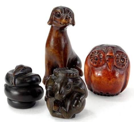 Four oriental carved wooden netsuke, to include one carved in the form of a cow or beast, a dog, a snake and an owl.