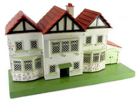 An early to mid 20thC mock Tudor dolls house, with metal grills to windows, the interior containing various items of furniture on a rectangular painted base, 84cm W.