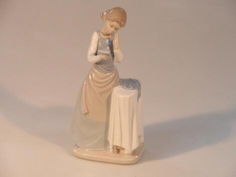 A Lladro figure of a young girl ironing