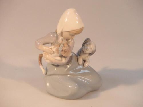 A Lladro figure group of a young girl with a cat and inquisitive puppy