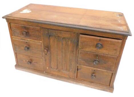 A Victorian pitch pine dresser base, the top with a moulded edge above a panel door, flanked by three drawers, to each side with turned wood handles on plinth base, (AF), 135cm W.