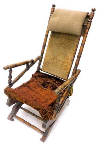 An American type walnut rocking chair, with a carpet upholstered back, velvet seat on castors. (AF)