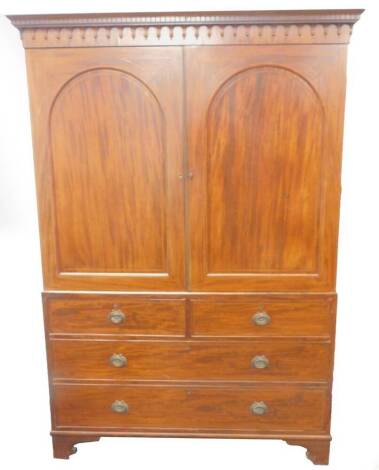 An early 19thC mahogany linen press, with dentil moulded bell husk pediment, two arched panelled doors with chevron inlay over two short and two long graduated drawers with cast brass oval handles and bracket feet, 207cm H, 140cm W.